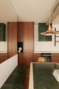 Modern kitchen with wooden cabinets, marble countertops, and a green marble floor.