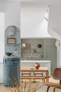 Modern living, dining, and kitchen space featuring marble countertops, wooden furniture, and ceramic ornaments.