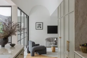 A modern living room with neutral-colored furnishings and a large window.