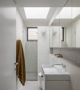 A minimalist bathroom featuring white terrazzo flooring and walls, with a white sink, toilet, and towel rack.