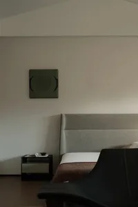 A minimalist bedroom with a gray upholstered bed and nightstand