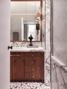 A modern bathroom featuring marble countertops, wooden cabinets, and patterned floor tiles.