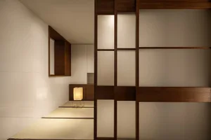 A minimalist residential interior featuring a paper lamp, tatami mat, and wood and fabric materials.