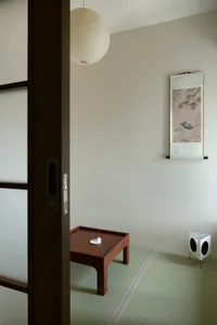 A minimalist residential interior with wooden furniture and a traditional hanging lantern.