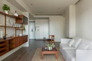 Modern minimalist living room with white furniture, wood accents, and a cozy atmosphere.