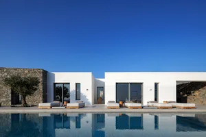 White minimalist vacation home with a pool and lounge chairs.