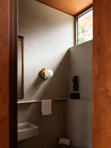 Modern bathroom with white square tiles, a wall-mounted light fixture, a mirror, and a window.