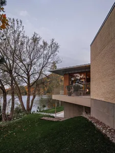 Modern house with a brick exterior overlooking a lake.