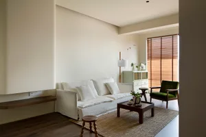A modern living room featuring a white sofa, wooden flooring, and a wooden coffee table.