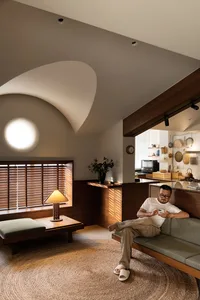 A modern living room with wooden furniture and a circular rug.
