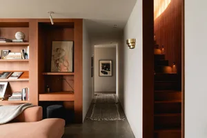 Modern living room featuring a sleek bookshelf with books and art, a cozy sofa, and a warm, minimalist design with wooden ele