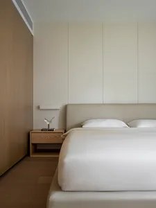 A modern minimalist bedroom with neutral tones and wood accents.
