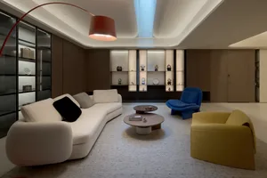 Minimalist living room with white sofa, blue chair, and round coffee table.