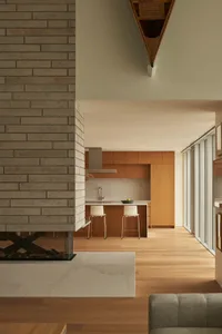 A modern residential kitchen features brick walls, wooden cabinets, and marble countertops.