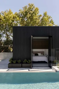 Modern wooden residential shed with large glass doors and a pool next to it.