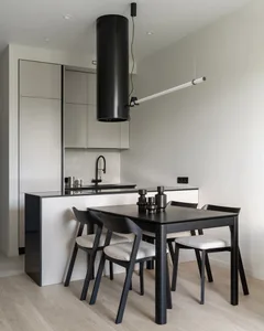 Modern kitchen with minimalist design featuring white glass cabinets, black kitchen island, and black dining table with white