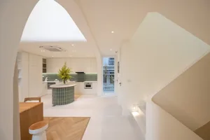 A minimalist kitchen with white cabinets and a green island.