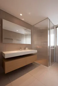A modern bathroom with a floating vanity and frosted glass shower enclosure.