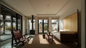 Modern interior living room with a wooden floor, white walls, large windows, and minimalist furniture, featuring a comfortabl