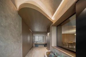 Modern lounge area with wooden seating, concrete walls, and vertical blinds