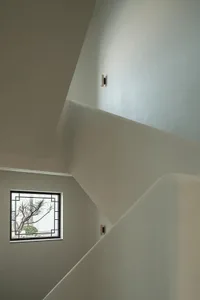 Modern concrete staircase with a window view of leafless trees.