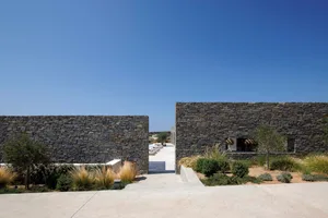 A modern residential exterior featuring stone walls and a clear blue sky.
