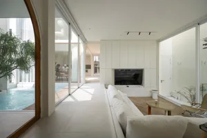 White living room with a large sofa, coffee table, and a television mounted on a wall.