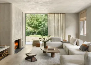 A minimalist living room with concrete walls, off-white fabric furniture, and wood accents.