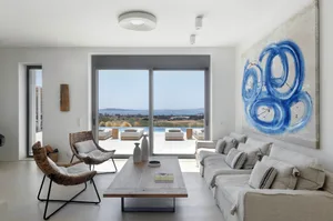 Modern, minimalist living room featuring a large blue abstract painting, a white sofa, and a wooden coffee table.