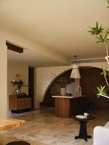 A minimalist residential interior featuring wooden furniture, stone flooring, and metal accents.