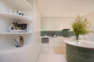 Modern minimalist residential kitchen with open layout and white surfaces.