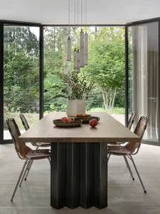 Modern dining room featuring a wooden table set with fresh apples and flowers.