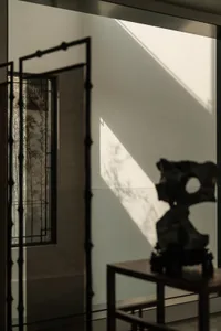 A modern entryway with wooden features and a shadowed bamboo plant in the background.