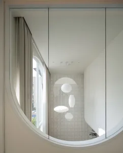 A minimalist interior design featuring a glass window with curtains and light fixtures.
