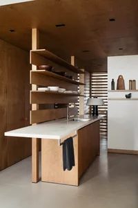 A modern kitchen featuring a minimalist white countertop and wooden furniture.