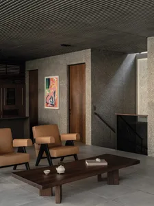 A modern living room with minimalist furniture and concrete walls and floor.