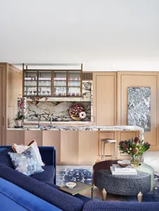 Modern living room kitchen with open concept, featuring marble, wood, and metal materials.