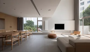 A modern living room featuring minimalistic furniture and a large wooden table with chairs.
