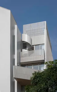 Modern minimalist residential building with aluminum panels and a spiral staircase.