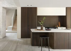 Modern minimalist kitchen with dark wood cabinetry and a white countertop featuring a vase with flowers and grapes.