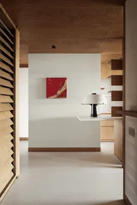 A minimalist office space with a concrete floor, wooden shelves, and a red abstract painting.