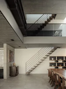 Modern interior design featuring a wooden staircase with concrete flooring and railings, creating a contemporary living space