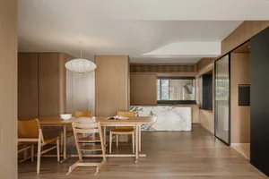 Modern, minimalist kitchen and dining area with wooden furniture and white marble countertops.