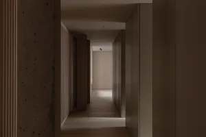 A minimalist hallway with wooden flooring and concrete walls.