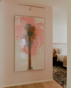 Minimalist bedroom featuring wooden furniture and a large framed artwork depicting a palm tree.