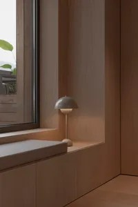 A minimalist window corner featuring wooden paneling and a small lamp.