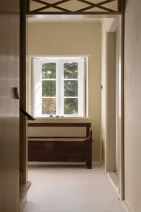 A minimalist window nook featuring wooden furniture and a view of a wooded area.
