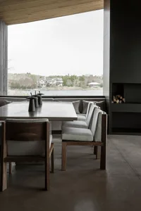 Modern dining room with wooden table and chairs, featuring a view of the water.