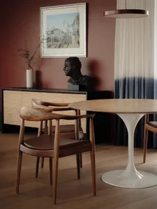 Modern dining room featuring a round wooden table and cushioned chairs.