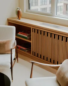 A modern interior design featuring wooden shelving and a window with books and a vase on the sill.